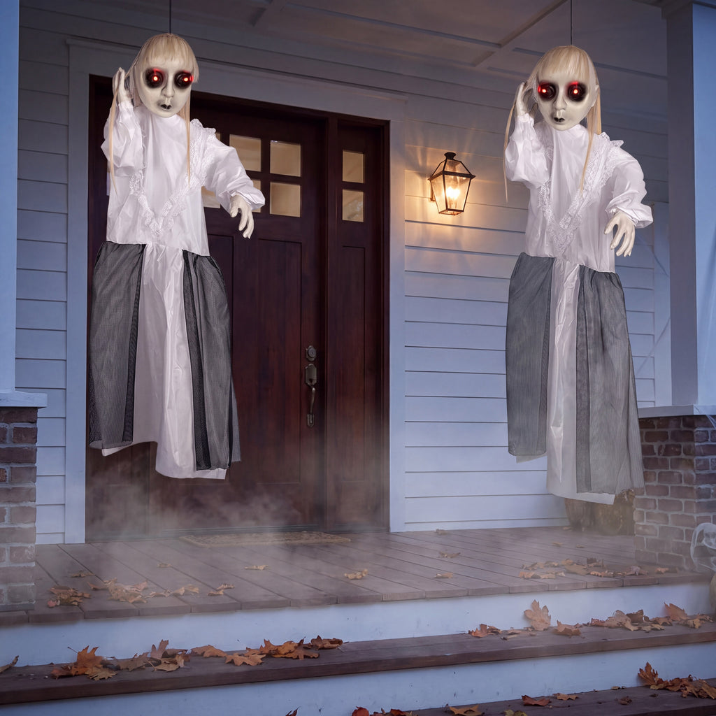 Two of the hanging ghost decorations flanking a dark wooden front door at dusk, showing their size against the doorway